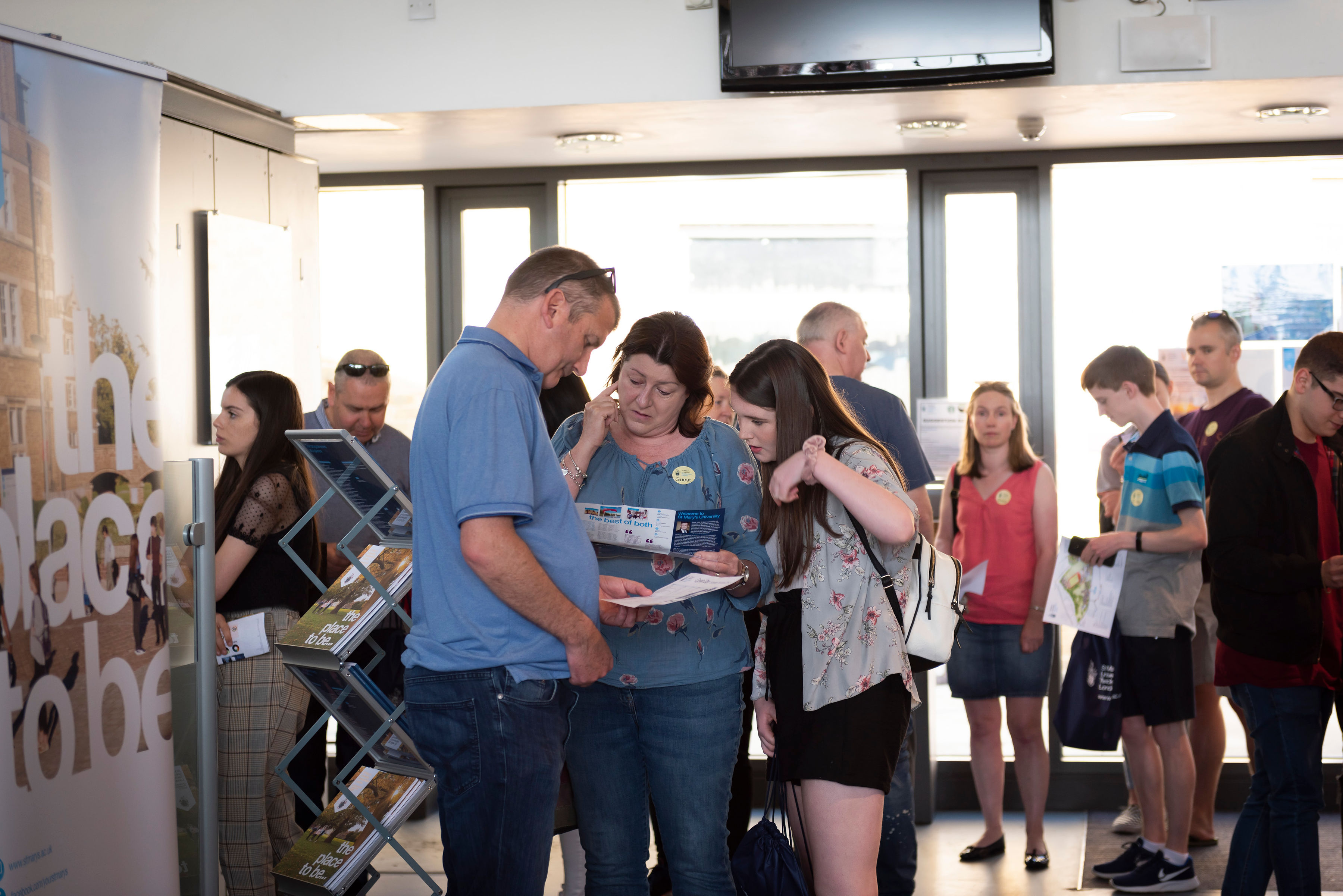 Parents and daughter planning their day with the Open Day leaflet at St Mary's University